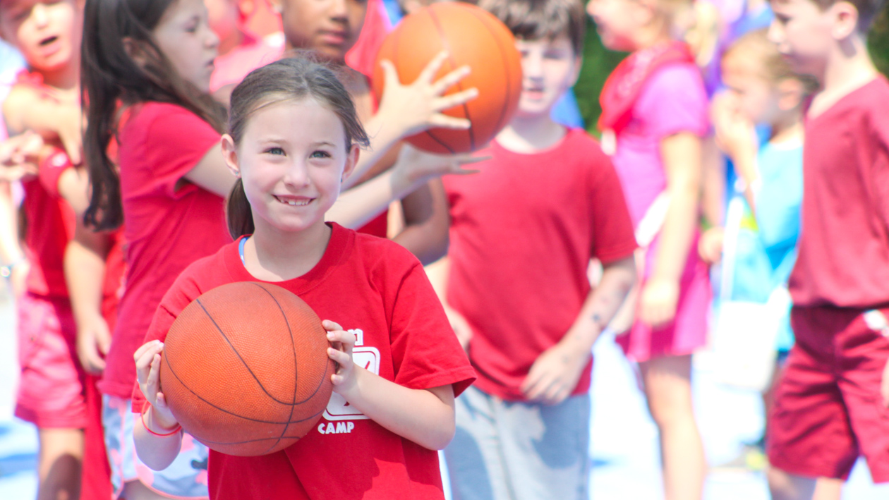 A girl holding a basketball with a red shirt.